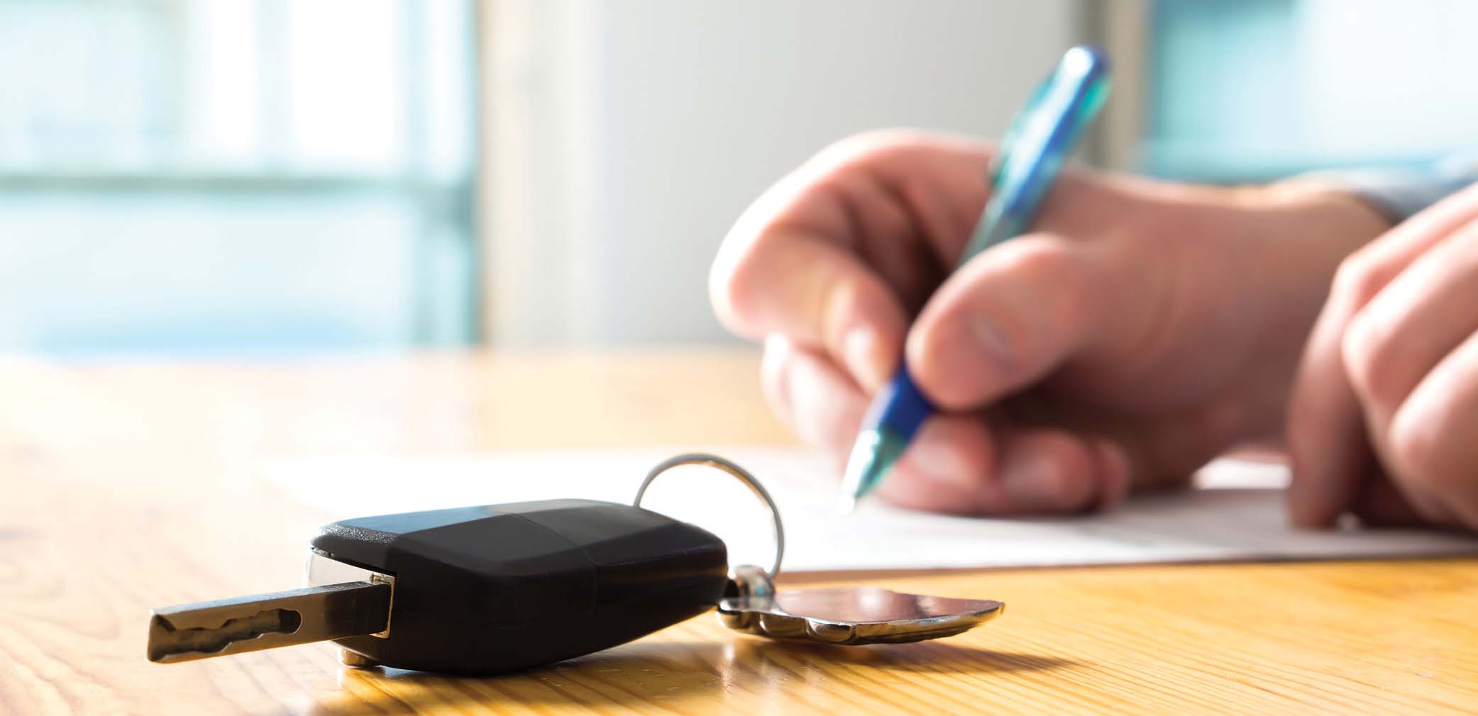 signing contract paperwork with automobile keys